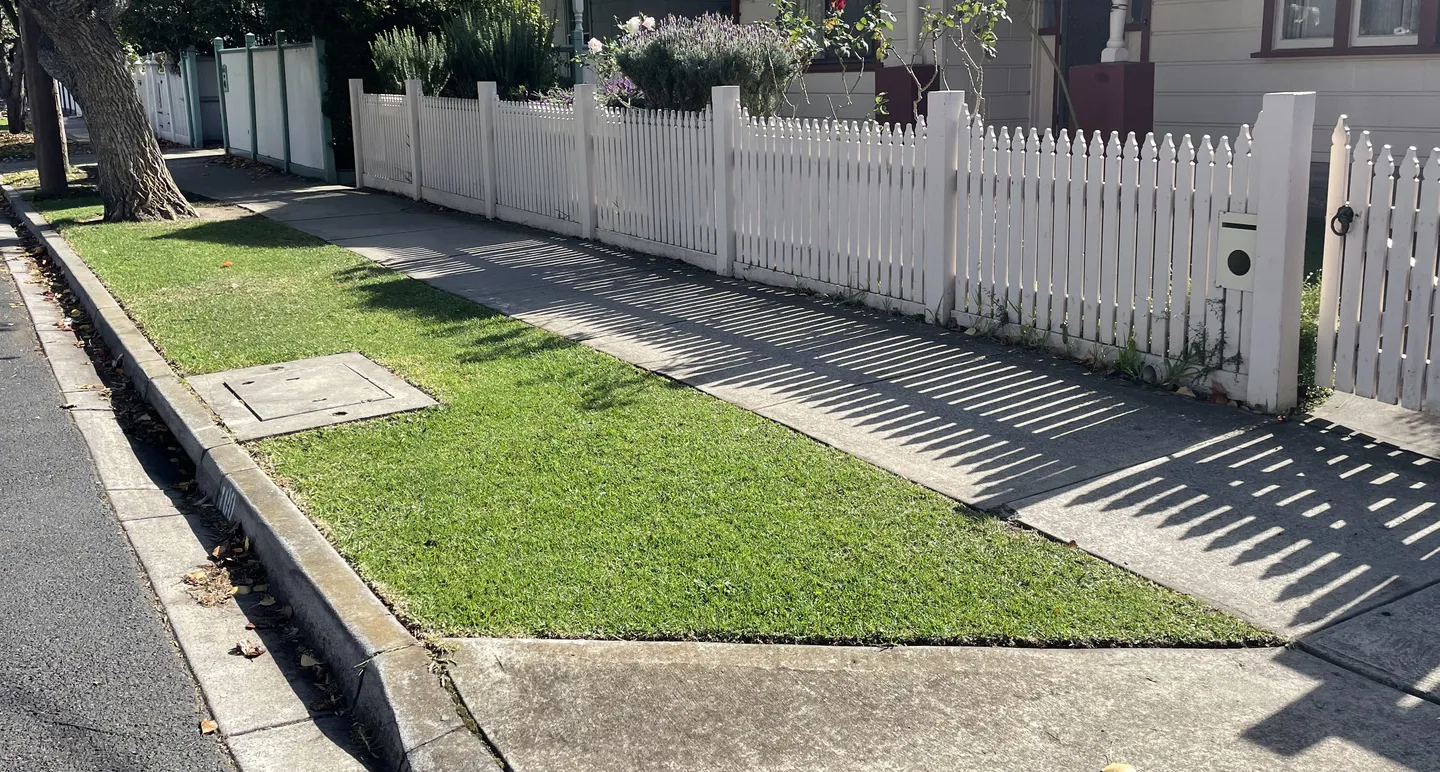 A neat street verge nature strip with mowed grass and straight edges against a concrete footpath